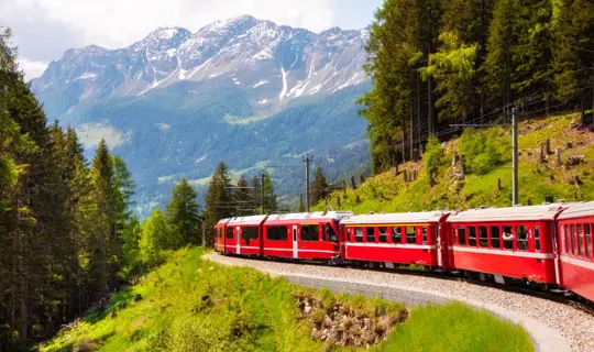 Red train moving in beautiful mountain landscape in Switzerland